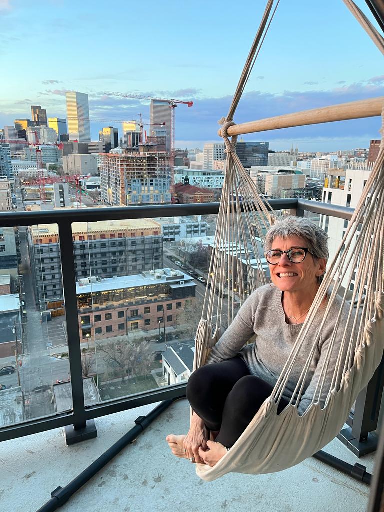 Sandy sitting on terrace in sling swing chair smiling